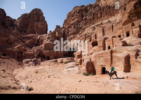 D'un âne de l'enfant en face de troglodytes à Pétra, Site du patrimoine mondial de l'UNESCO, la Jordanie, Moyen-Orient Banque D'Images