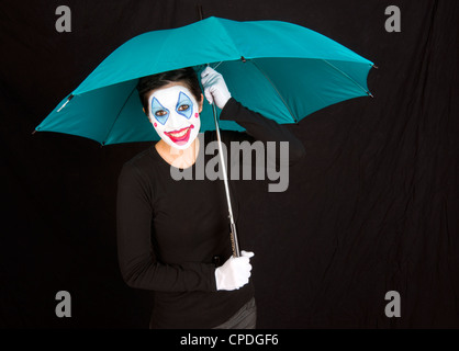 Un clown heureux abris sous un parapluie coloré Banque D'Images