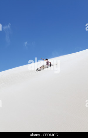 Une femme monte un sandboard, sandboarding sur une dune de sable blanc, Lancelin, Australie occidentale, Australie, Pacifique Banque D'Images