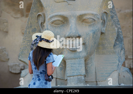 L'étude d'un touristiques statue de le pharaon Ramsès II, temple de Louxor, Louxor, Thèbes, Site du patrimoine mondial de l'UNESCO, l'Égypte, l'Afrique Banque D'Images