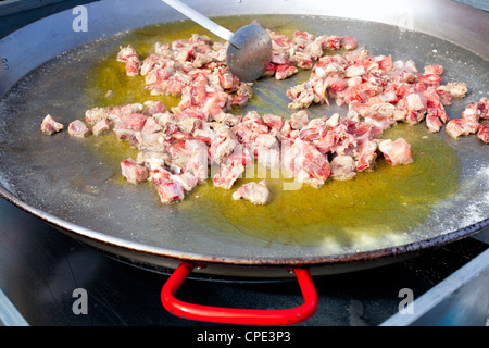 La Paella de l'Espagne Premiers pas la cuisson grande casserole avec du poulet et de l'huile Banque D'Images