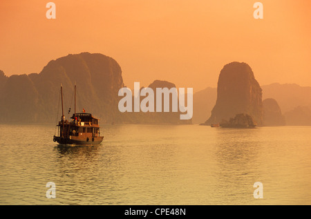 La voile traditionnelle à travers l'archipel calcaire au coucher du soleil, la baie d'Ha Long, au nord-est, le Vietnam, l'Indochine, en Asie du sud-est Banque D'Images