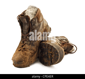 Paire de chaussures de randonnée marron sale dans la boue agglutinée isolé sur un fond blanc Banque D'Images