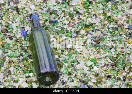 Une bouteille de vin qui a échappé à l'aplatisseur repose sur un lit de particules de verre à un centre de recyclage, UK Banque D'Images