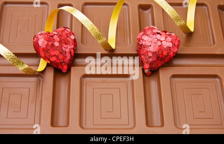 Grande barre de chocolat belge avec des coeurs et des rubans d'or pour la célébration d'une journée spéciale. Banque D'Images