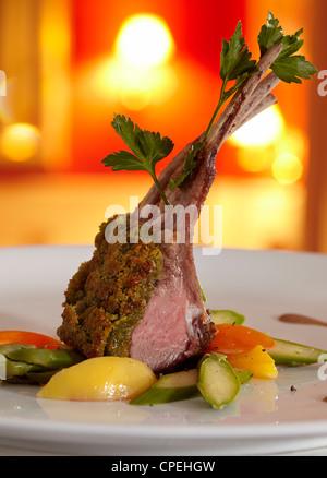 Carré d'agneau en croûte d'herbes, servi à la ratatouille et Port wine-sauce. Close-up. Dans l'arrière-plan d'un restaurant en couleur rouge Banque D'Images