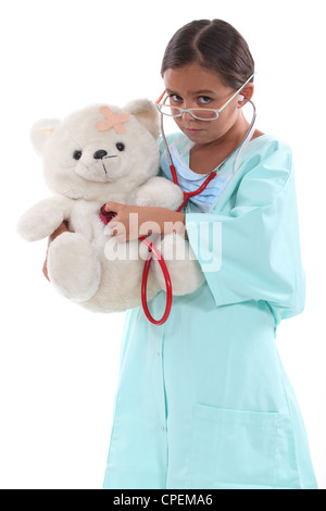 Petite fille habillée en nurse holding teddy bear Banque D'Images