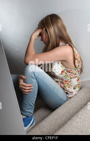 Jeune fille assise sur un escalier sombre vue arrière Banque D'Images