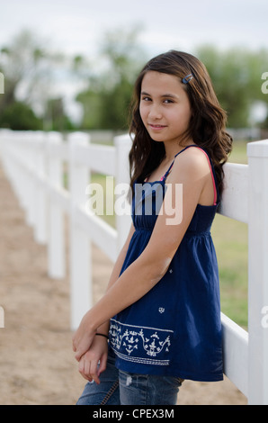 De 12 ans mixed race girl (asiatique/Caucasian) pose près d'une clôture blanche Banque D'Images