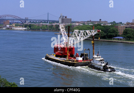 Remorqueurs poussant barge, chaland, plate-forme flottante, grue de construction East River New York City, New York. Pont Robert F Kennedy et pont Hell Gate. Banque D'Images