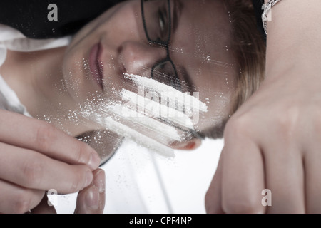 Femme junkie toxicomanes reflétée dans un miroir et lignes de cocaïne. Banque D'Images