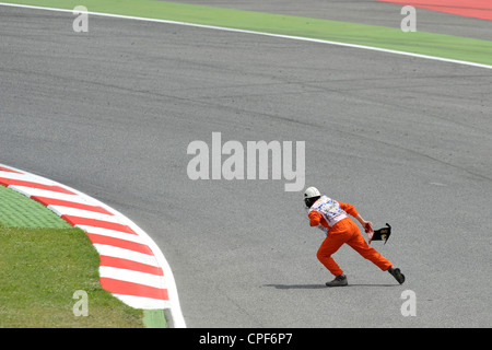 Un commissaire de pistes supprime la pièce d'une voiture de course lors du Grand Prix de Formule 1 d'Espagne 2012 Banque D'Images