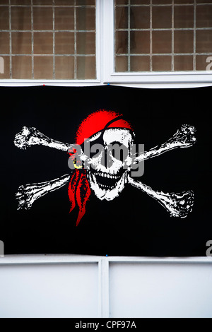 Drapeau pirate Jolly Roger dans fenêtre bar, Brixham, Devon, Angleterre Banque D'Images