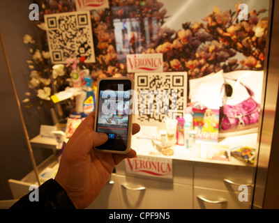 Votre nouveau style, l'homme de la numérisation d'un QR code avec le smartphone de produit en vitrine, d'acheter le produit et nous vous le livrerons à la maison. Banque D'Images