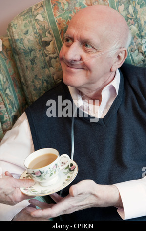 Un homme âgé avec un accompagnant ou une infirmière offrant une bonne tasse de thé Banque D'Images