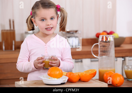 Petite fille faire du jus d'orange. Banque D'Images