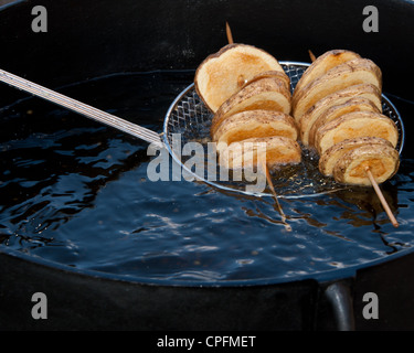 Tranches de pommes de terre cuites dans la fondue de pitchfork. Banque D'Images