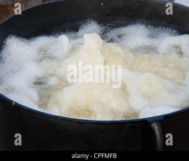 À partir de l'huile bouillante les tranches de pommes de terre dans la fondue de pitchfork. Banque D'Images