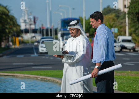 Homme d'affaires arabe avec ordinateur portable et architect standing sur rue. Banque D'Images