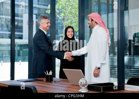 Homme d'arabe et de l'ouest businessman shaking hands au bureau, young à proximité. Banque D'Images