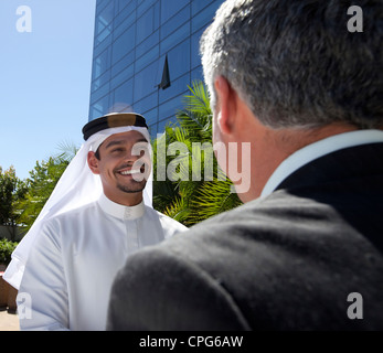 Homme d'affaires de l'ouest et arabe en face du bâtiment, en souriant. Banque D'Images