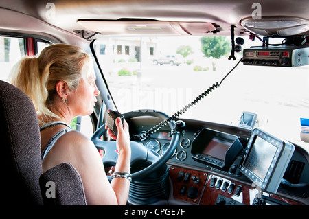 Femme conducteur du camion dans un gros camion en conversation sur la C.B. radio. Banque D'Images