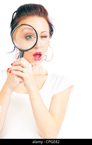 Jolie jeune femme à travers une loupe isolé sur un fond blanc. Banque D'Images