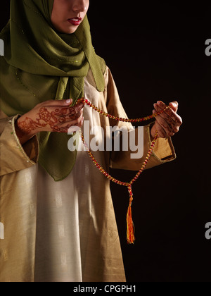 Young woman holding chapelet, close-up Banque D'Images