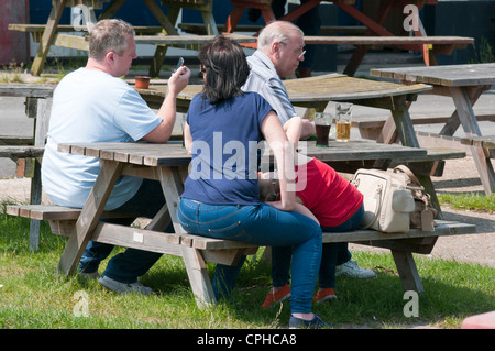 Famille siégé ensemble à l'extérieur, au soleil dans un jardin Pub Banque D'Images
