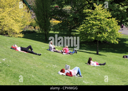 Les jeunes femmes se détendre sur l'herbe et le soleil brille, les jardins de Princes Street Edinburgh Scotland UK Banque D'Images