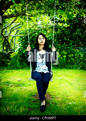 Le punjabi woman on swing in garden Banque D'Images