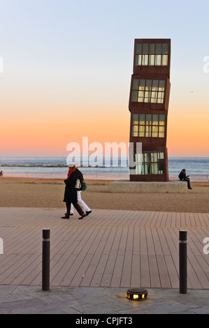 Barcelone, Espagne - Décembre 2011 : les gens à pied ou reste sur la célèbre plage de la Barceloneta au soir près de la sculpture d'art moderne. Banque D'Images