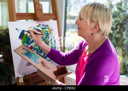 Happy retired woman painting on canvas pour le plaisir à la maison Banque D'Images