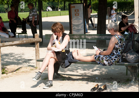 Paris, France - un jeune et un vieux livre de lecture des femmes sur un banc. Banque D'Images