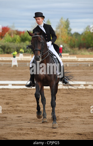 Une jeune femme avec son étalon alezan sur un concours de dressage Banque D'Images