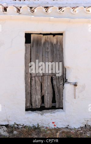 Vieille porte de grange en bois rugueux dans mur blanc de basse-cour, Minorque, Espagne Banque D'Images