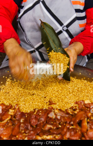 Woman making Zongzi, nourriture chinoise faite de riz gluant avec différents fourrages et enveloppés dans des feuilles de palmier, Shanghai, Chine Banque D'Images