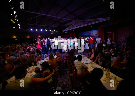 Les touristes sur la danse musique grecque traditionnelle au cours d'une émission de variété dans une taverne restaurant près de Hersonissos aussi comme Chersonisos et Hersonisos situé dans la côte nord de l'île de Crète en Grèce Banque D'Images