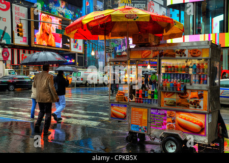 Rue typique de vente du vendeur de hot dogs de panier dans la pluie New York Ville Manhattan emblématique icône à l'extérieur à l'angle de route Banque D'Images