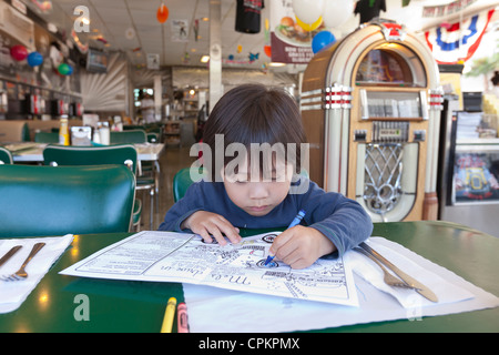 Un jeune garçon asiatique en coloriant un menu enfants's Diner Banque D'Images