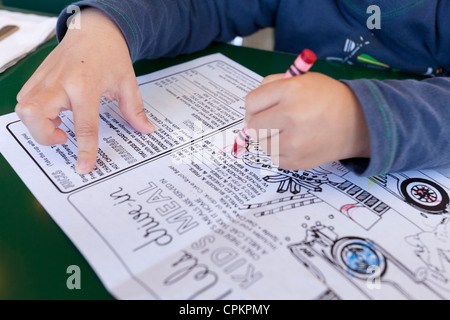 Libre d'un jeune garçon en coloriant un menu diner enfants Banque D'Images