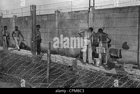 Les internés du camp de construction les murs du camp de concentration de Dachau, sous la surveillance d'un garde SS, 1933 (photo n/b) Banque D'Images