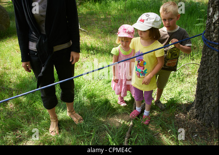 La formation des enfants et marcher sur la corde - slacline avec mère parc d'été Banque D'Images