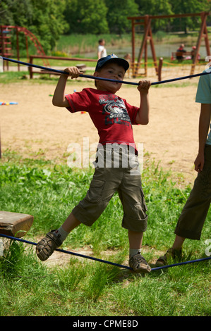 La formation des enfants et marcher sur la corde - slacline avec mère parc d'été Banque D'Images