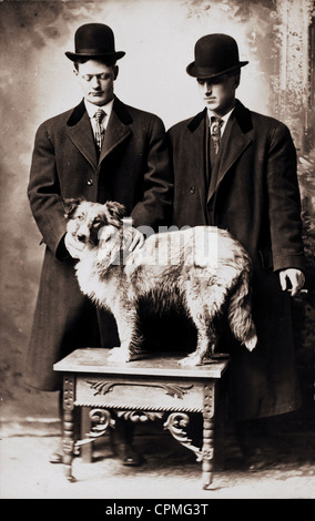 Deux hommes bien habillés et chien debout sur le tableau Banque D'Images