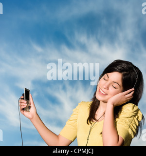Young woman listening to music via son téléphone portable Banque D'Images