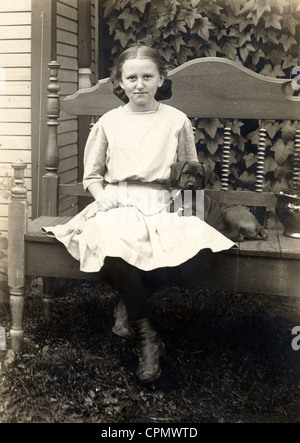 Petite fille assise sur un banc avec petit chien Banque D'Images