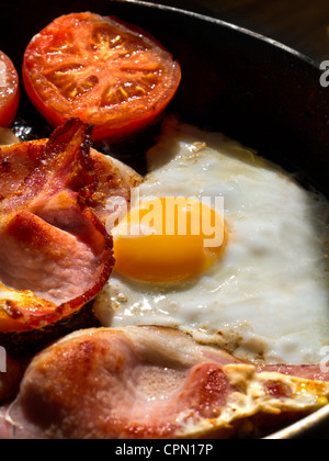 Rayon de soleil illumine l'oeuf bacon organique et les tomates à la poêle dans la poêle chaude en cuisine Banque D'Images