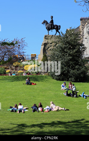 Les jeunes se détendre et profiter du soleil dans les jardins de Princes Street, Edinburgh Scotland UK Banque D'Images