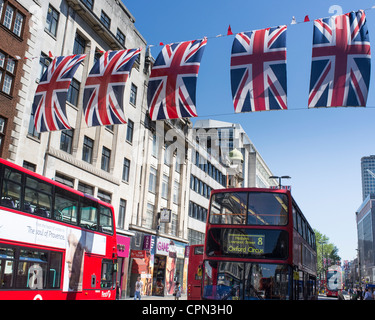 London bus à impériale rouge passer sous les drapeaux Union Jack sur Oxford Street Banque D'Images